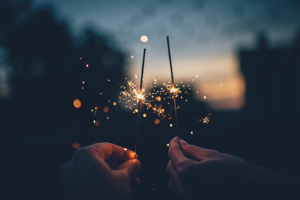 Picture of 2 people holding sparklers close together lit at dusk