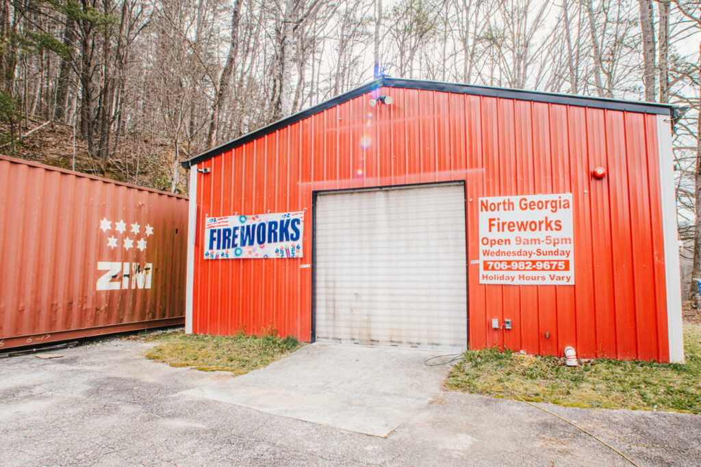utside of North Georgia Fireworks building with a Sign that say "North Georgia Fireworks Open 9am-5pm Wednesday-Sunday 706-982-9675 Holiday Hour Vary" and the garage door closed